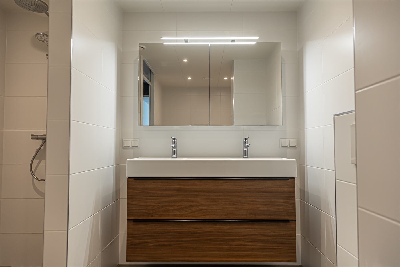 Lichte badkamer met dubbele wastafel en spiegelkast