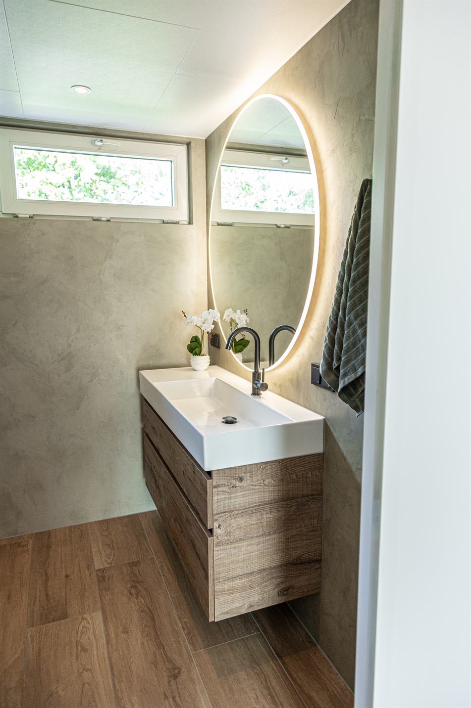 Lichte badkamer met ronde spiegel en houten wastafelmeubel